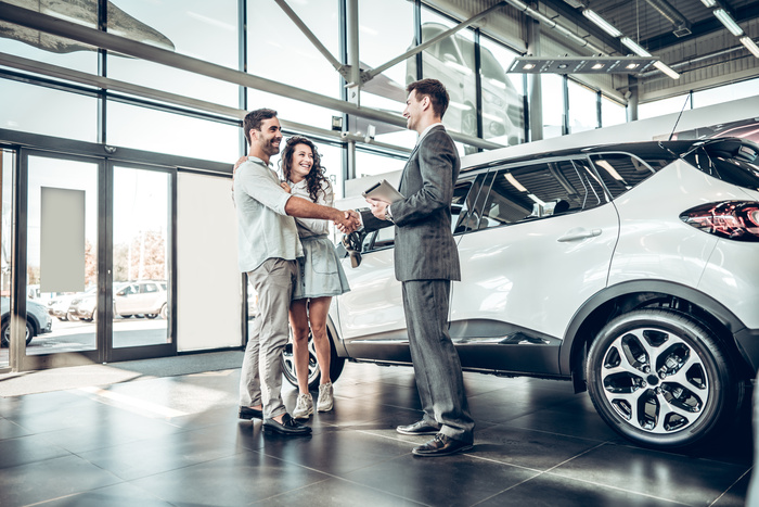 Young couple shaking hands with auto broker consulting after successful car buying